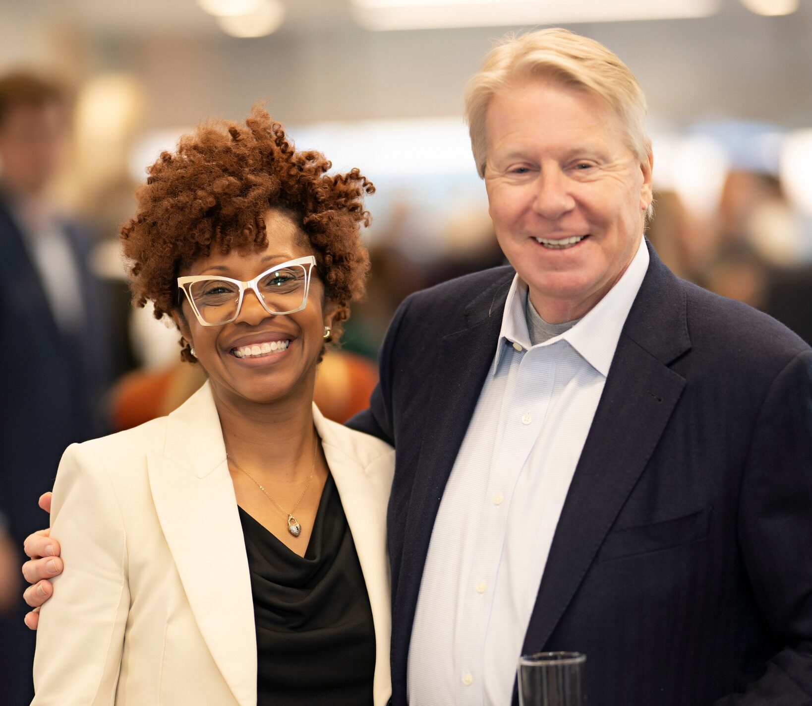 A woman and a man at a cocktail party smiling at the camera